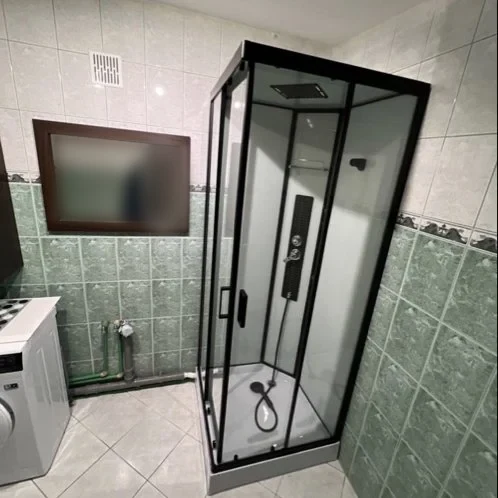 Łazienka z czarną kabiną prysznicową i pralką — DobryHydraulik Kraków