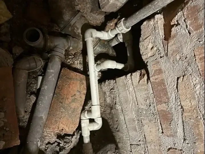Stare rury żeliwne w ceglanej ścianie — DobryHydraulik Kraków